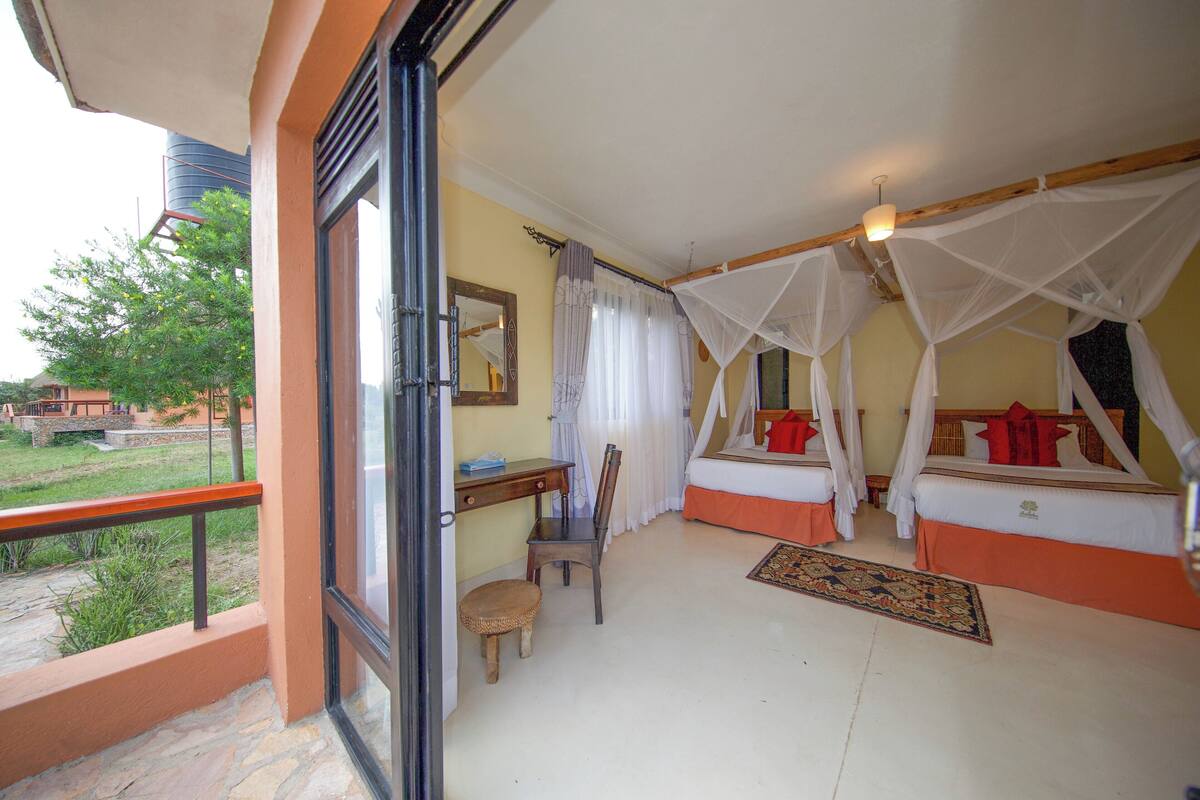 Una habitación con una cama bajo un dosel, un escritorio con una silla y vistas al exterior.