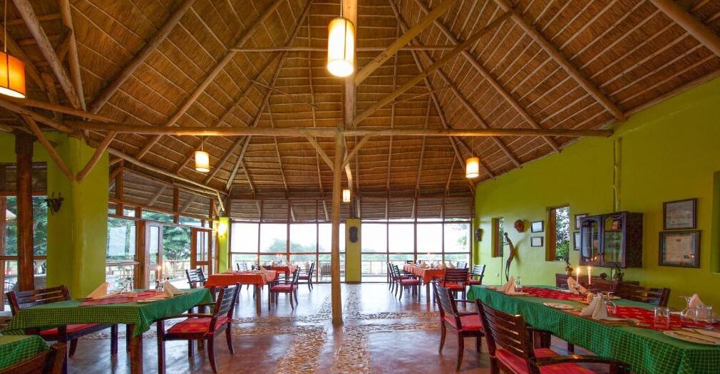 A spacious dining area with high ceilings and large windows, tables set for dining, and a view of the outdoors.