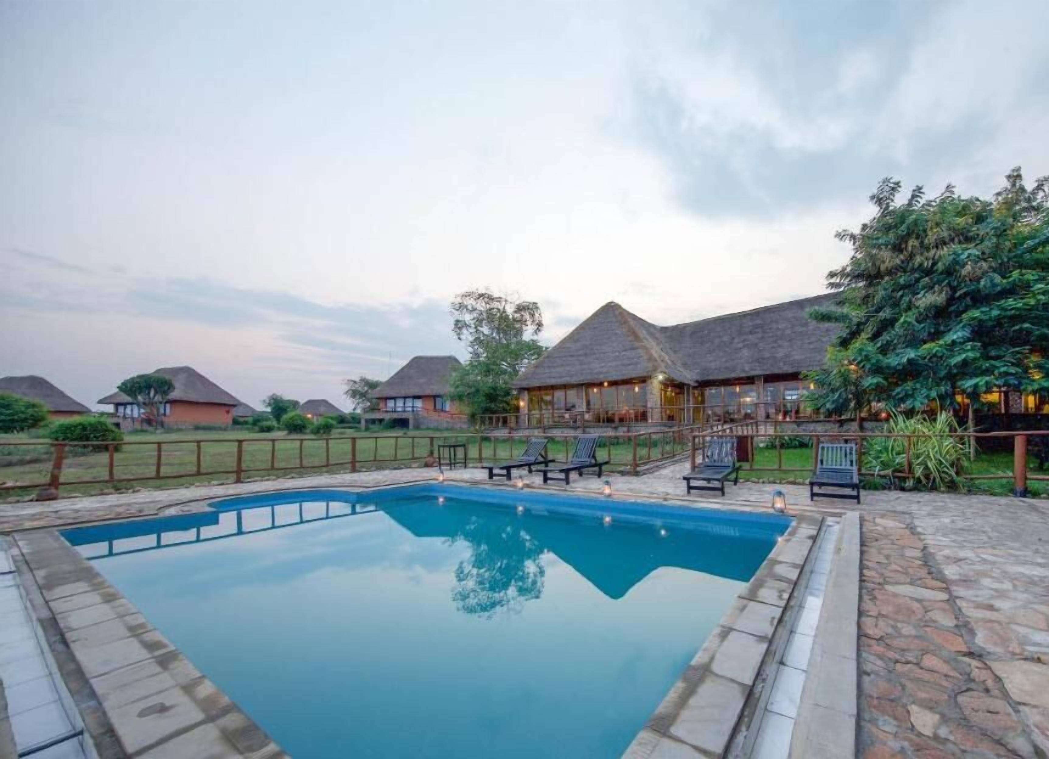A swimming pool with lounge chairs and a building with a thatched roof.