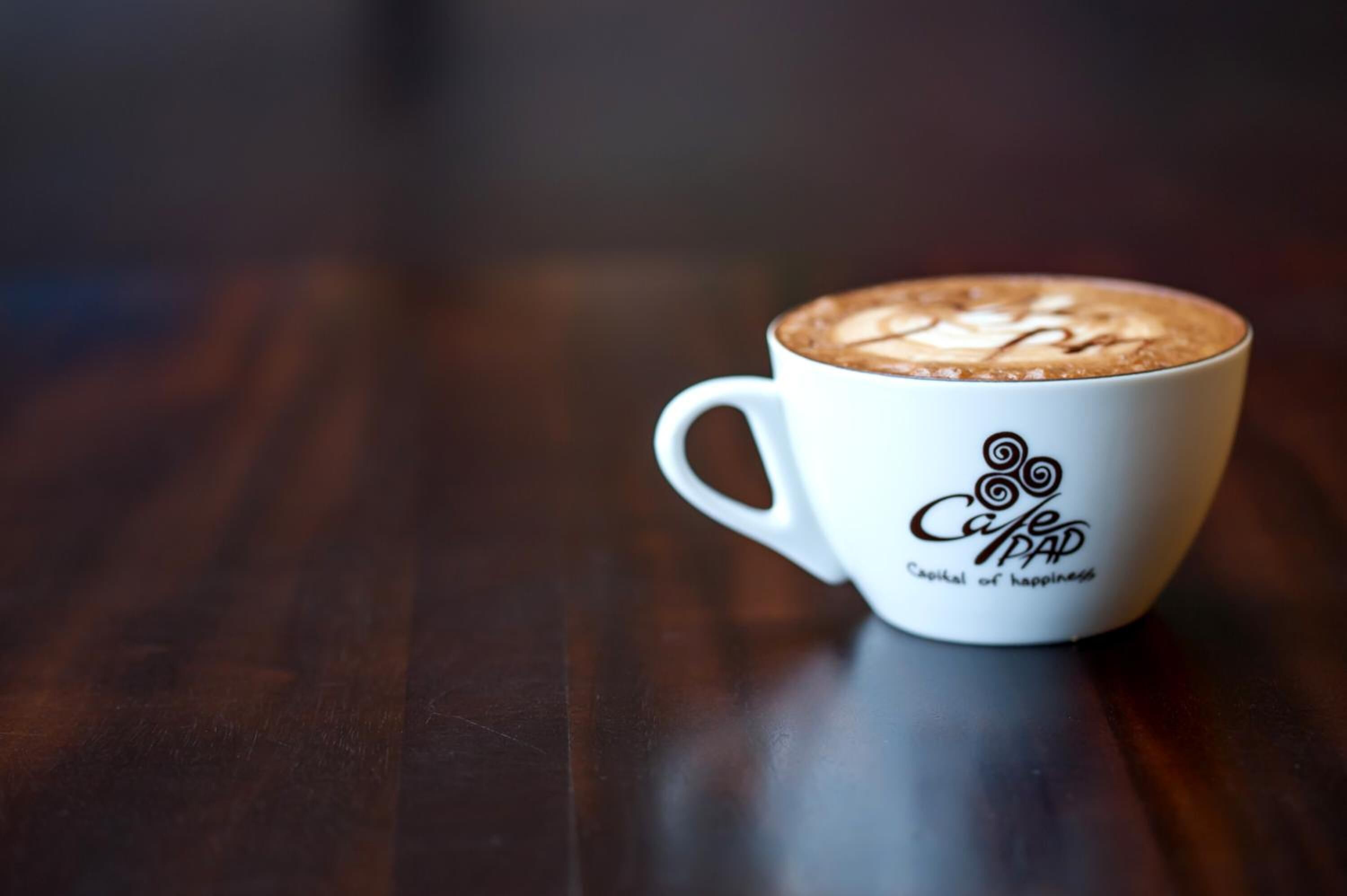 A white cup with a logo and text on a wooden surface.