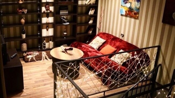 A cozy living room with a red sofa, a coffee table, and a bookshelf filled with books and decorative items. - Apartment on Aghmashenebeli Ave. (Tbilisi)