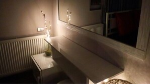 A room with a long, narrow bed, a bedside table with a lamp, a mirror, and a radiator. - Apartment on Aghmashenebeli Ave. (Tbilisi)