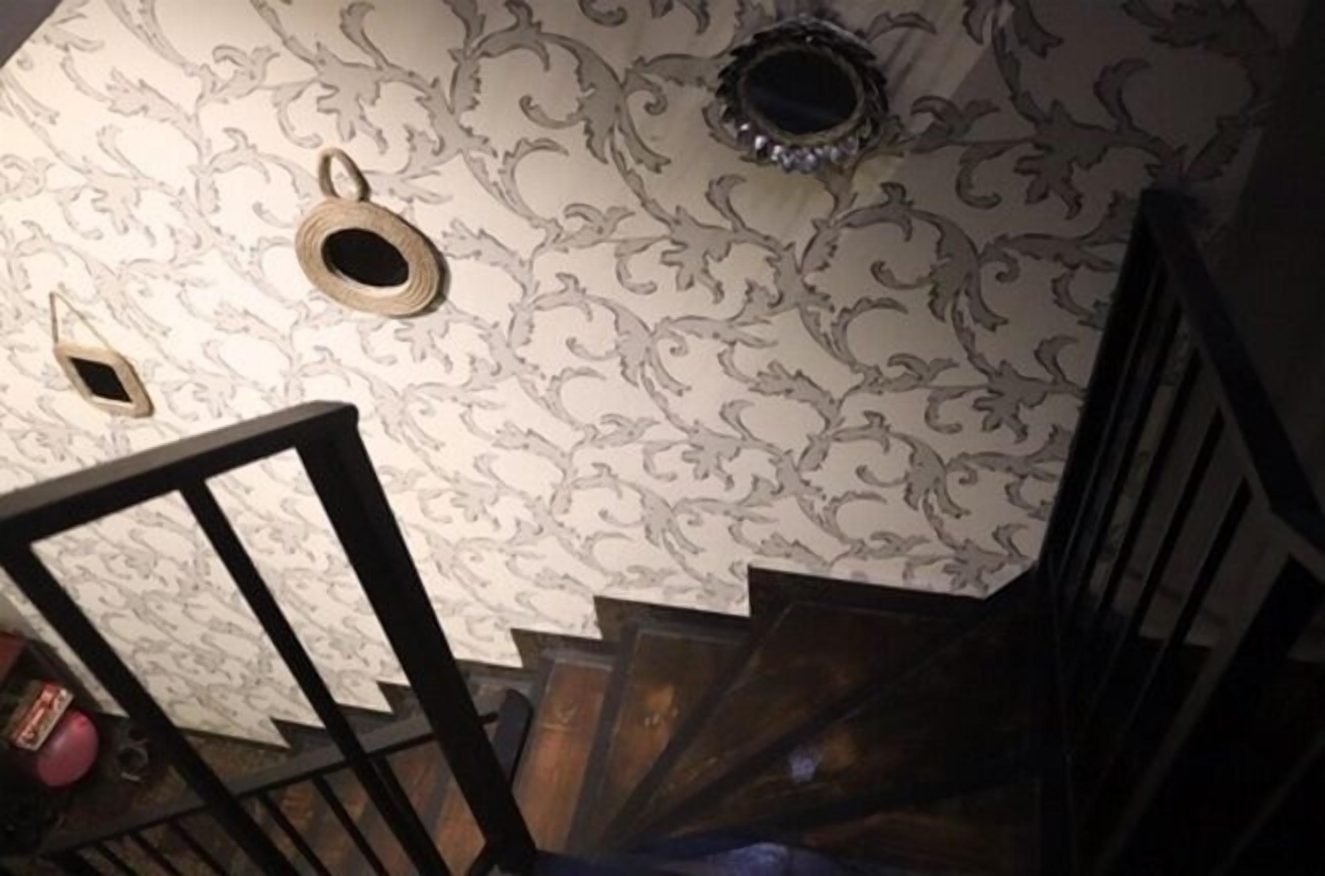 Un escalier avec un papier peint à motifs et une rampe en bois.