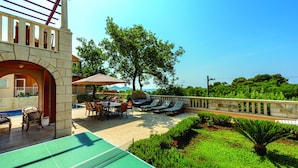 An outdoor patio with a pool table, seating area, and lounge chairs.