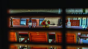 A cozy room with a wooden bench, a small table with a vase of flowers, and a bottle of liquor.