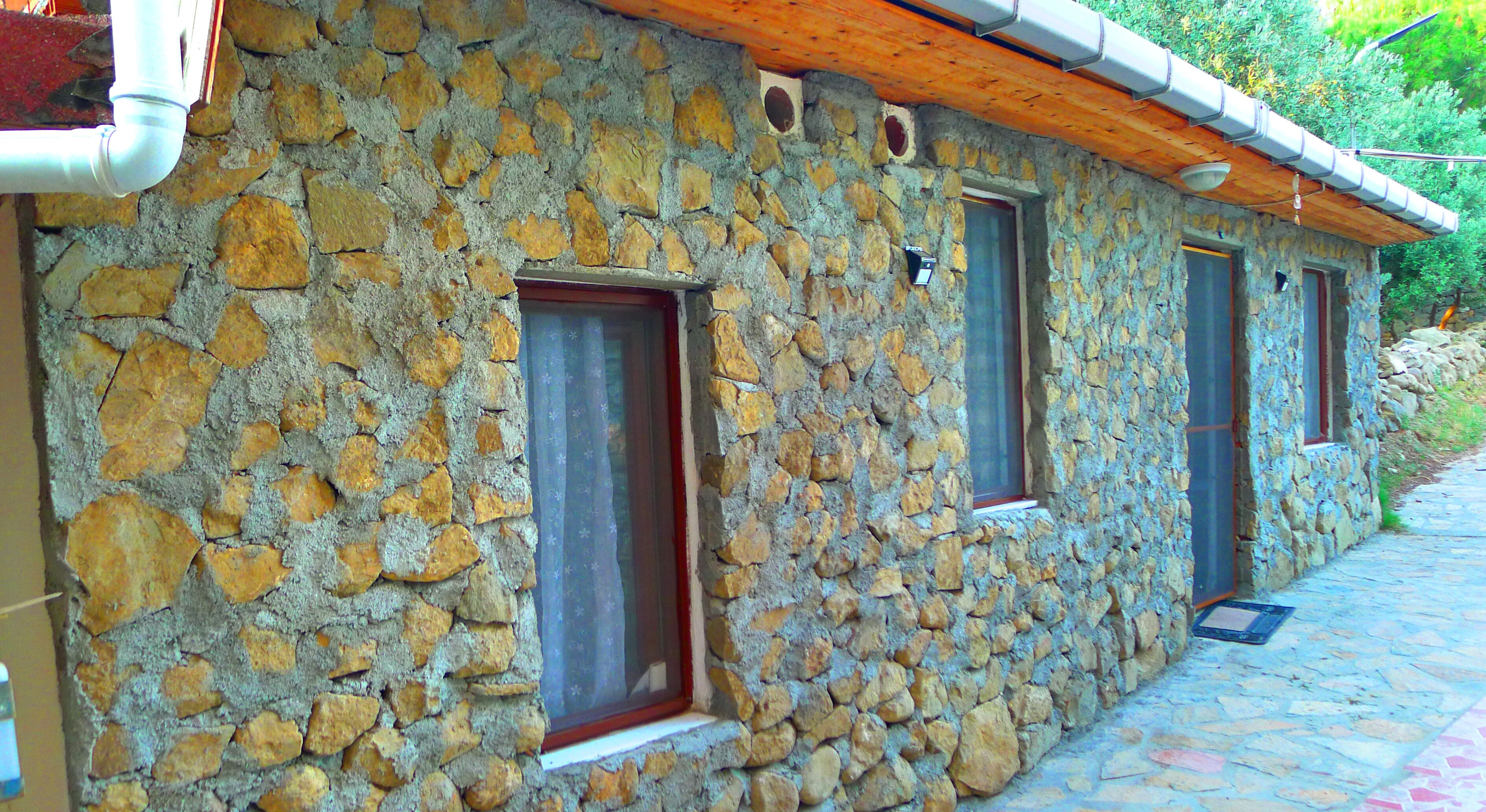 A stone building with three windows and a wooden roof.