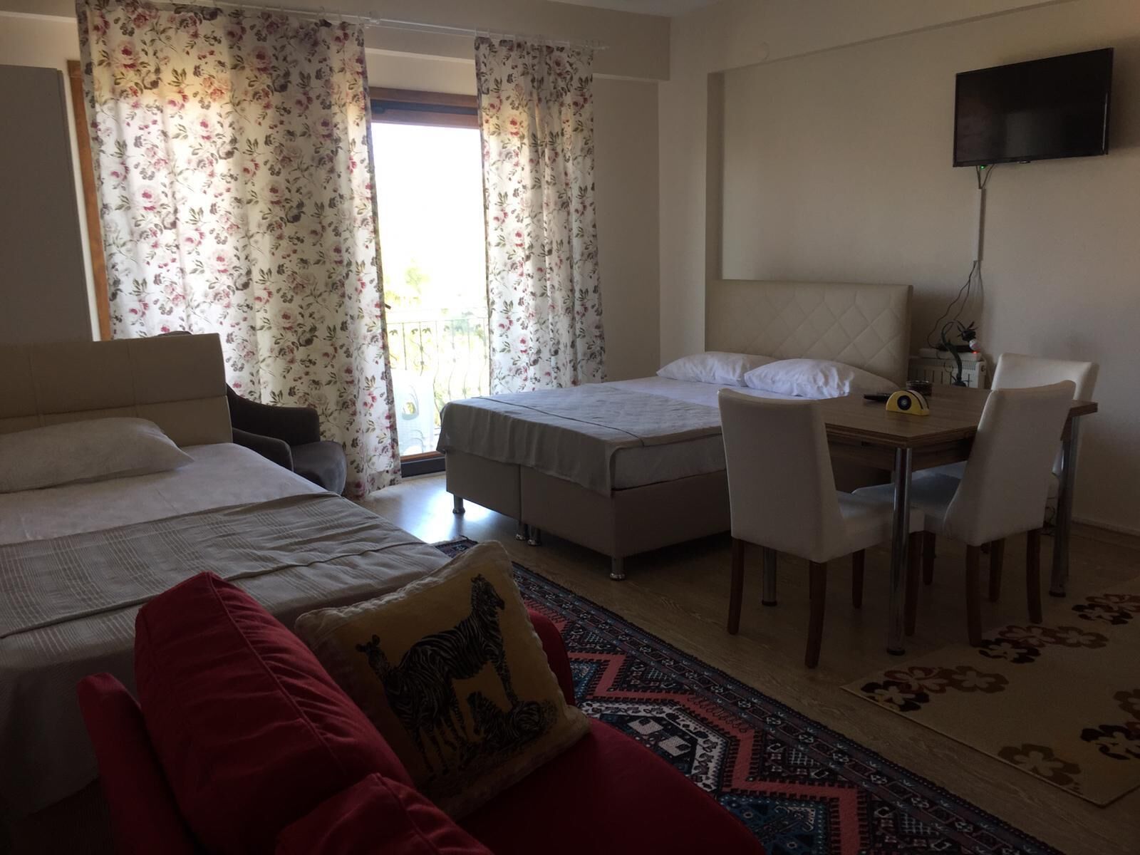 Habitación de hotel con dos camas, un escritorio, una silla, un televisor y una ventana con cortinas.