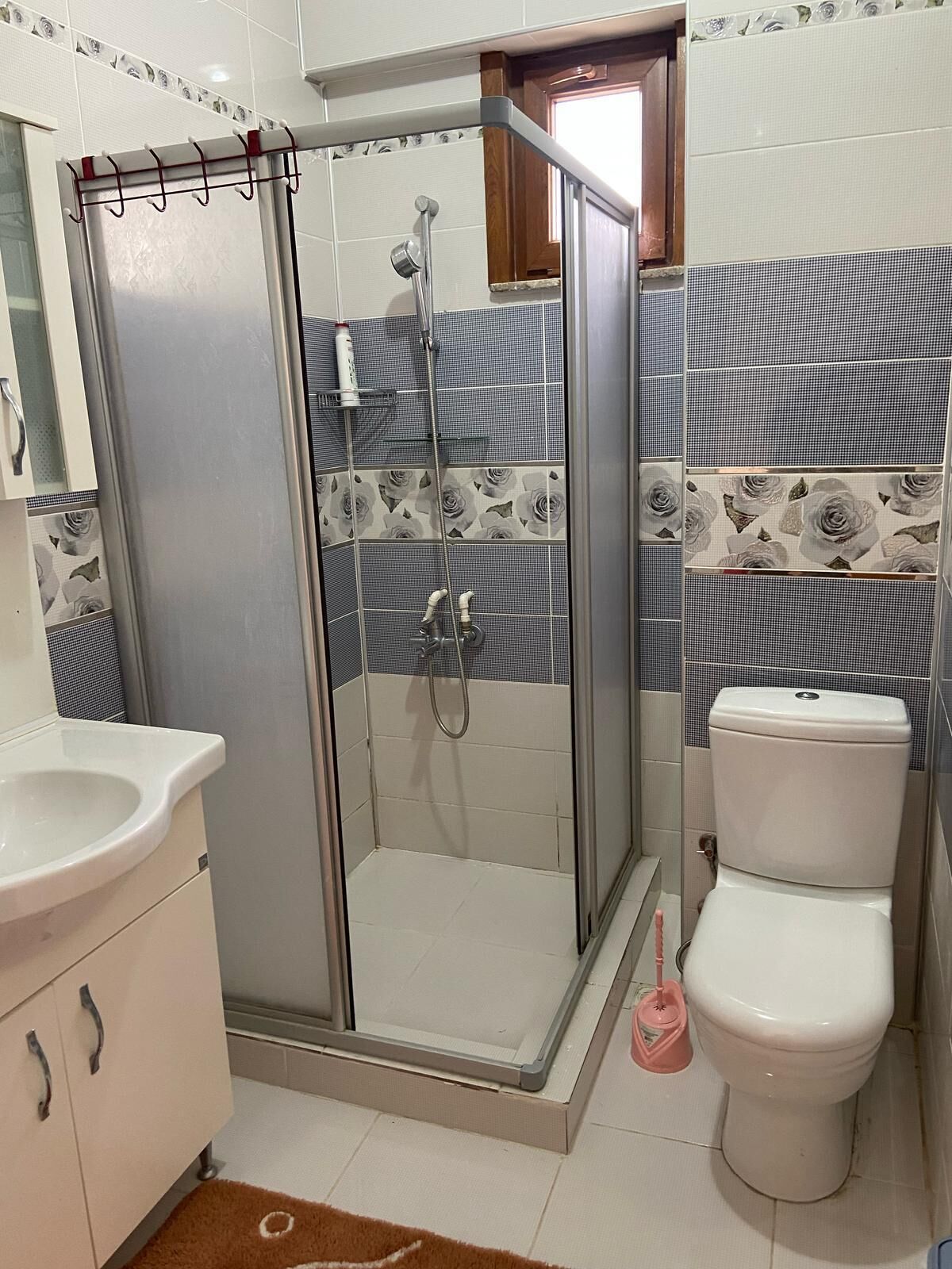 A bathroom with a glass-enclosed shower, a toilet, and a sink.