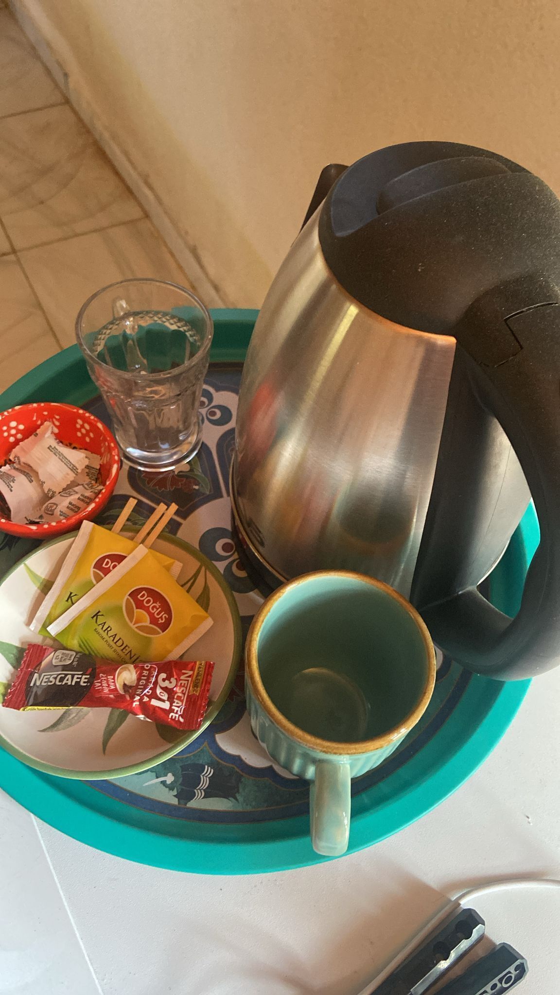 Ein Tisch mit Teekanne, Tasse, Glas, einem Teller mit Essensportionen und einer Schüssel.