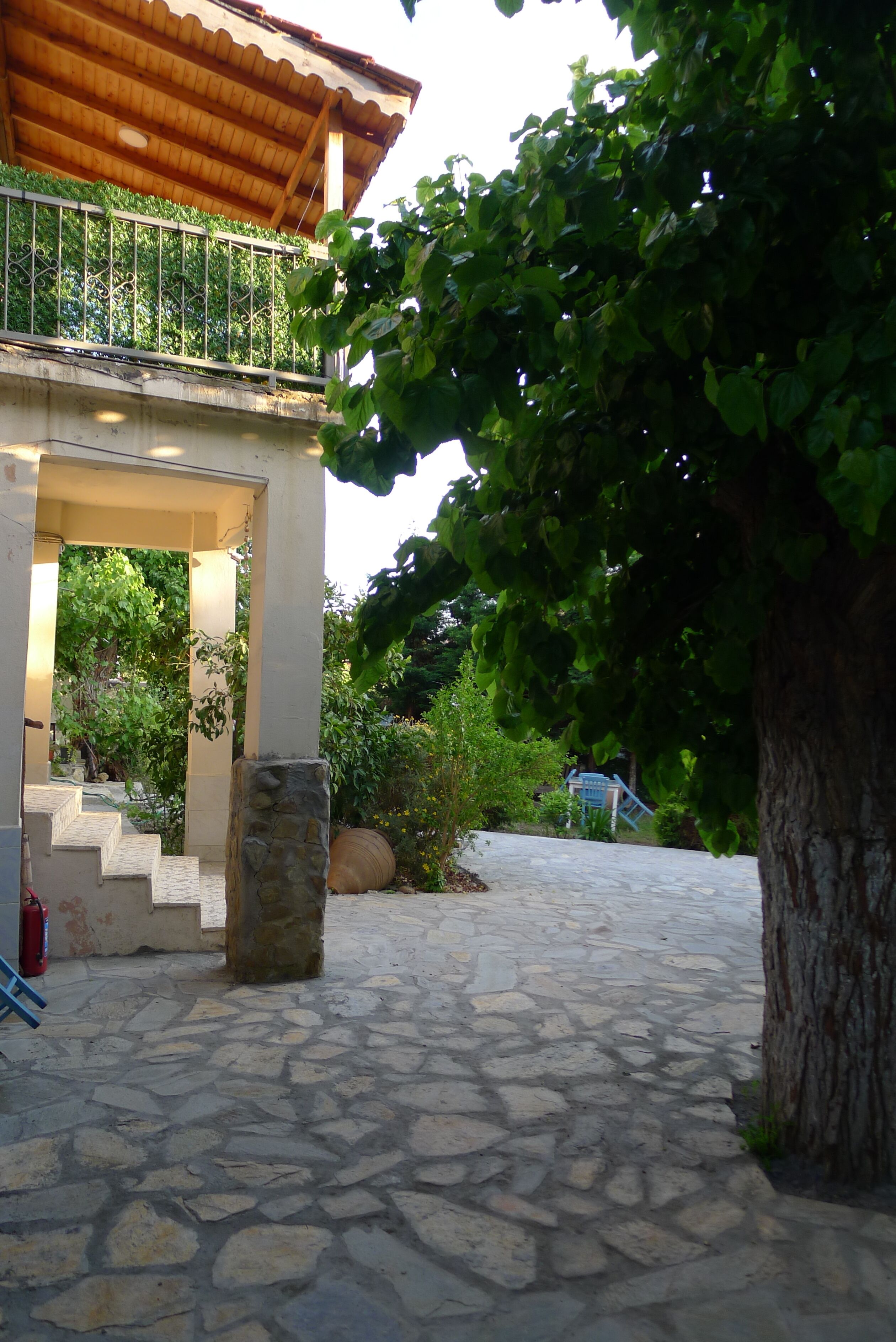 A stone-paved pathway leading to a building with a wooden roof and a balcony.