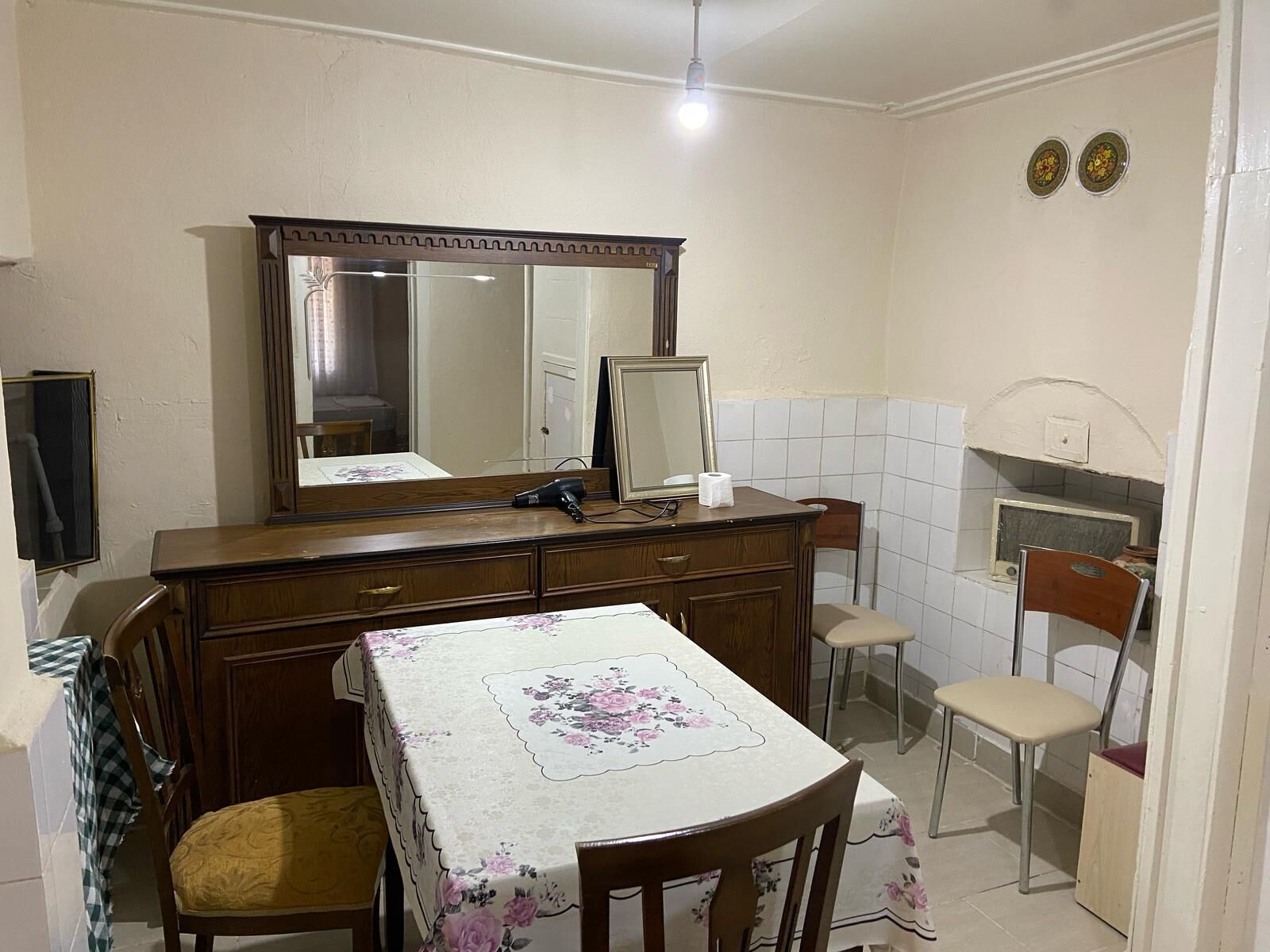 A small, compact kitchen with a wooden table, chairs, and a large mirror above the counter.