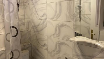 Un baño con inodoro, lavamanos, ducha y espejo.