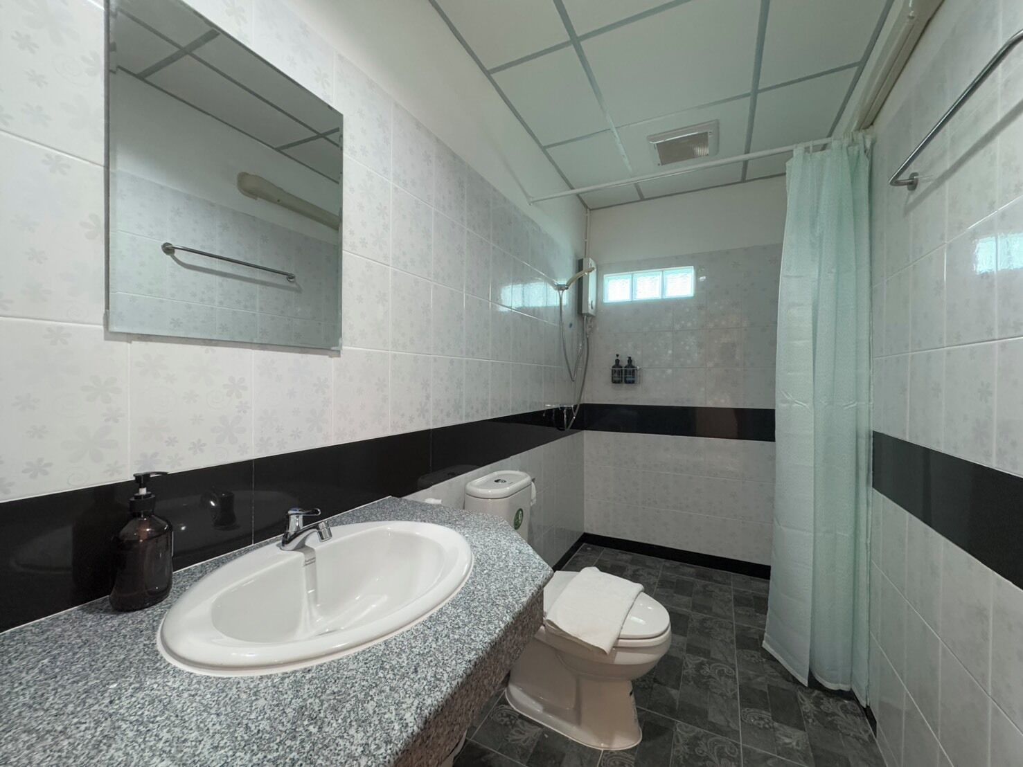 A bathroom with a granite countertop sink, a toilet, and a shower.