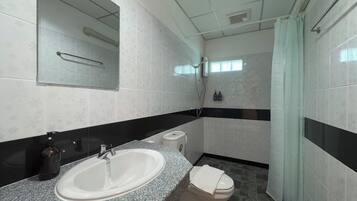 A bathroom with a granite countertop sink, a toilet, and a shower.