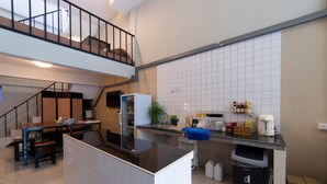 Ett modernt kök med en central köksö, en inbyggd ugn och en mängd olika köksmaskiner. En trappa leder upp till en övre våning.