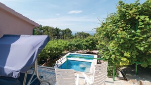 A pool area with a view of the sea, surrounded by greenery and a building.