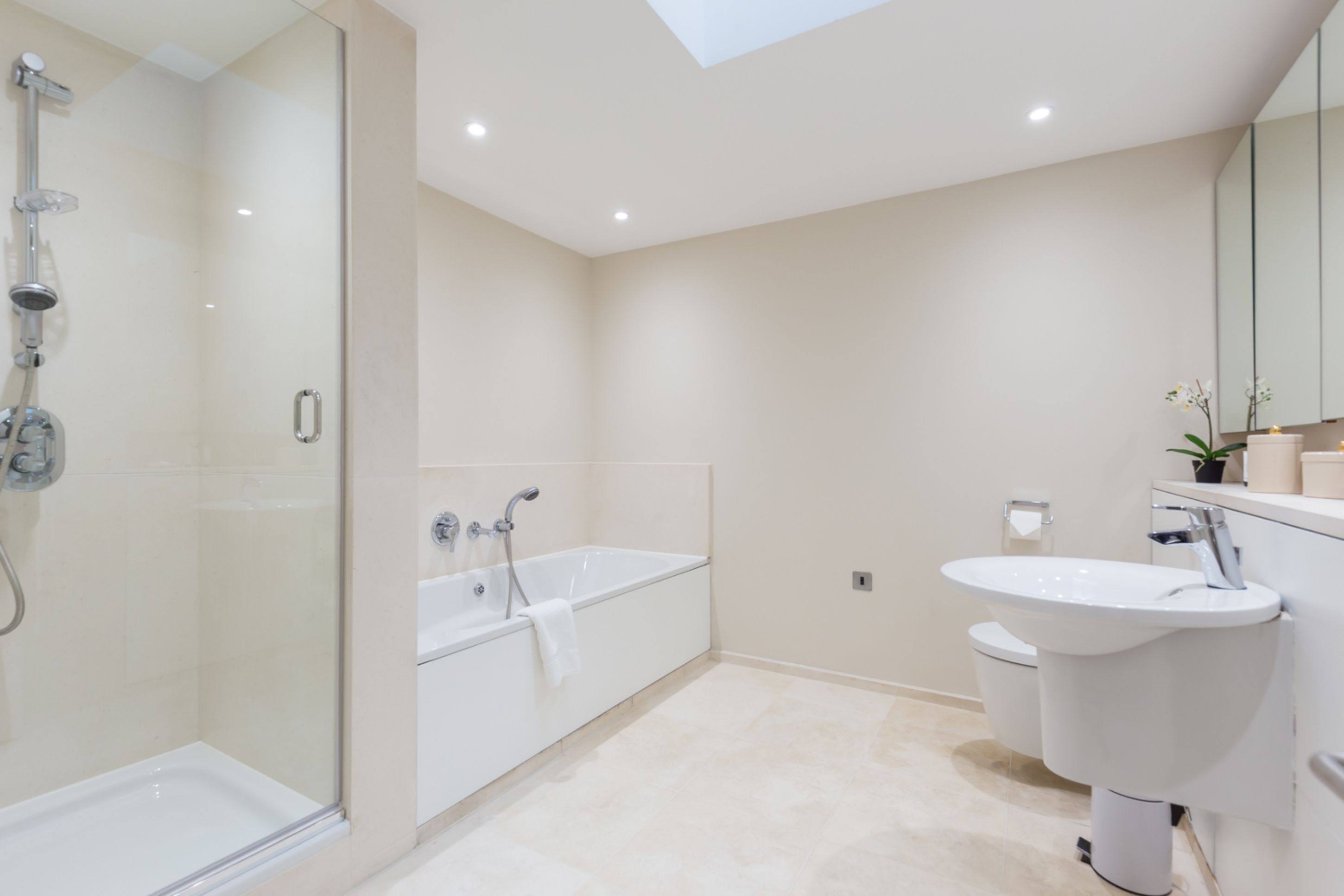 Une salle de bain moderne dotée d’une douche à parois de verre, d’une baignoire sur pieds et d’un lavabo fixé au mur.