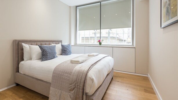 A modern bedroom with a large bed, a window with a view, and a framed picture on the wall. - Urban Chic - Exeter (London)