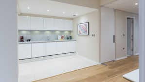 A modern kitchen with white cabinets, a marble countertop, and a framed picture on the wall. - Urban Chic - Exeter (London)