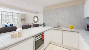 A modern kitchen with white cabinetry, a marble backsplash, and a built-in oven. - Urban Chic - Exeter (London)