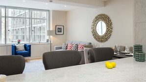 A modern living room with a dining area, large windows, and a decorative mirror. - Urban Chic - Exeter (London)