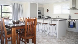 Una cocina moderna con una isla central, taburetes de bar y una mesa de comedor con sillas.
