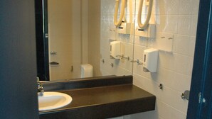 A bathroom with a white toilet, a sink, and a mirror above it. There are soap dispensers on the wall. - Solborg sommerpensjonat (Lindesnes)