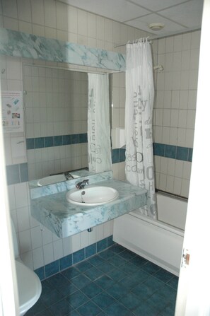 Une salle de bain avec un lavabo blanc, un miroir et un sol carrelé de carreaux bleus.
