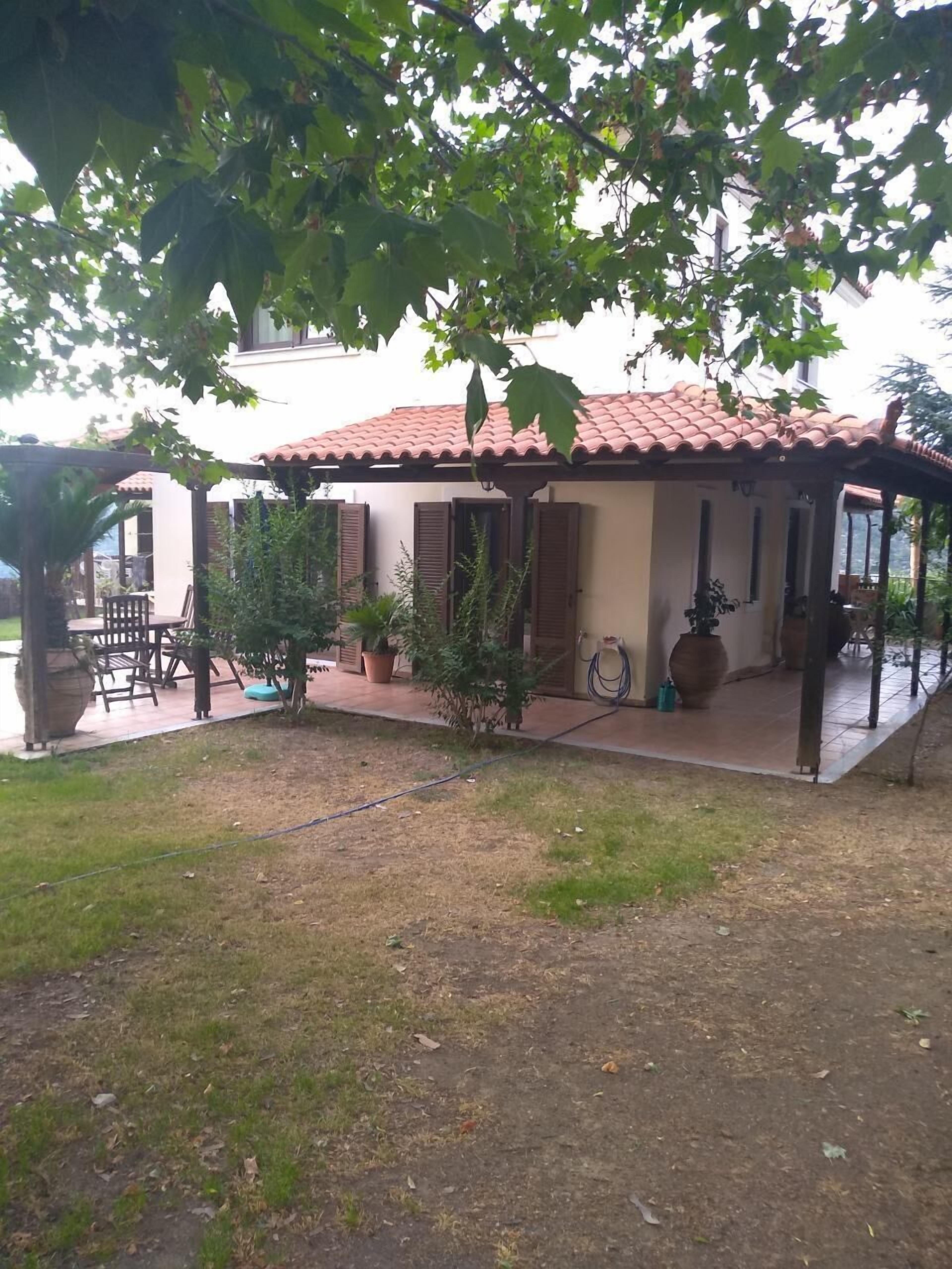 Un espace extérieur aménagé avec une pergola, des plantes en pot et une table de patio, le tout abrité.