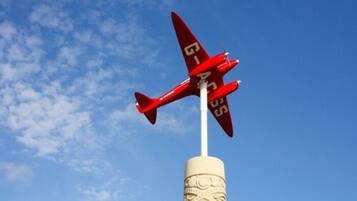 A red airplane model with the text "GIAC" on its wings, mounted on a white cylindrical base with intricate carvings.