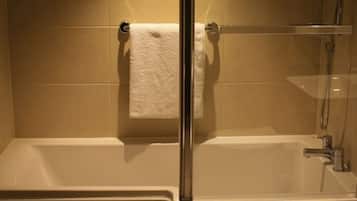 Un baño con bañera, cabina de ducha de vidrio y una toalla colgada en un toallero de metal.