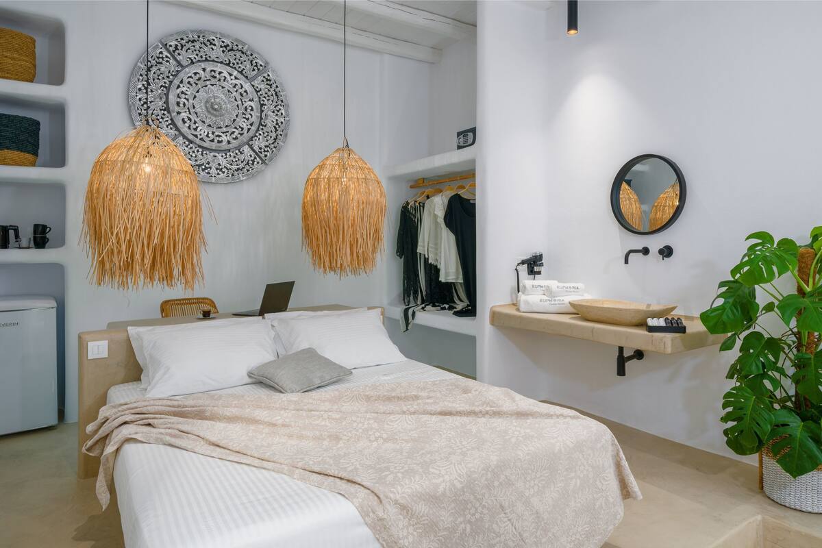 A modern bedroom with a bed, bedside table, lamp, wardrobe, and a large plant.