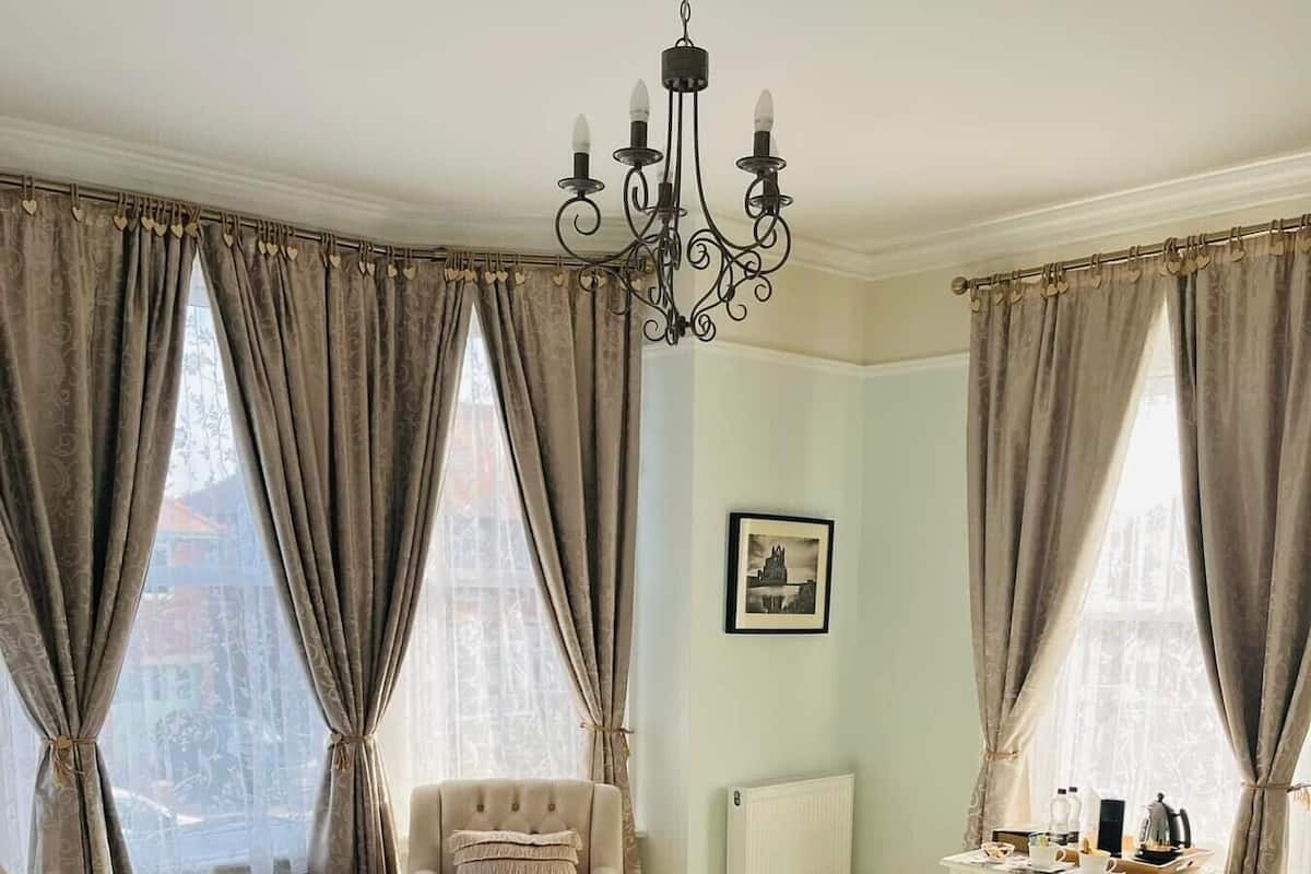 Une chambre à coucher avec un grand lit, une chaise, une commode et un lustre.