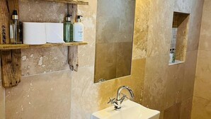 Ein Badezimmer mit einem weißen Waschbecken, einem Spiegel und Regalen mit Toilettenartikeln.