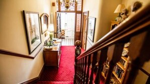 Eine Treppe mit rotem Teppich, die zu einem Raum mit einer Holztür und einem Chandelier führt.