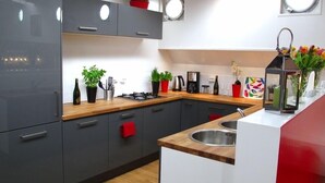 A modern kitchen with grey cabinets, a wooden countertop, and a red towel hanging on the door. - Boathotel Rotterdam Seven (Rotterdam)