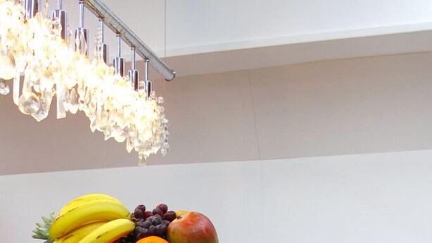 A wooden dining table with a fruit bowl containing bananas, grapes, and an apple. White chairs are around the table. - Boathotel Rotterdam Seven (Rotterdam)