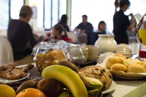 Una mesa de buffet con diversas opciones de comida, incluyendo frutas, pasteles y pan.