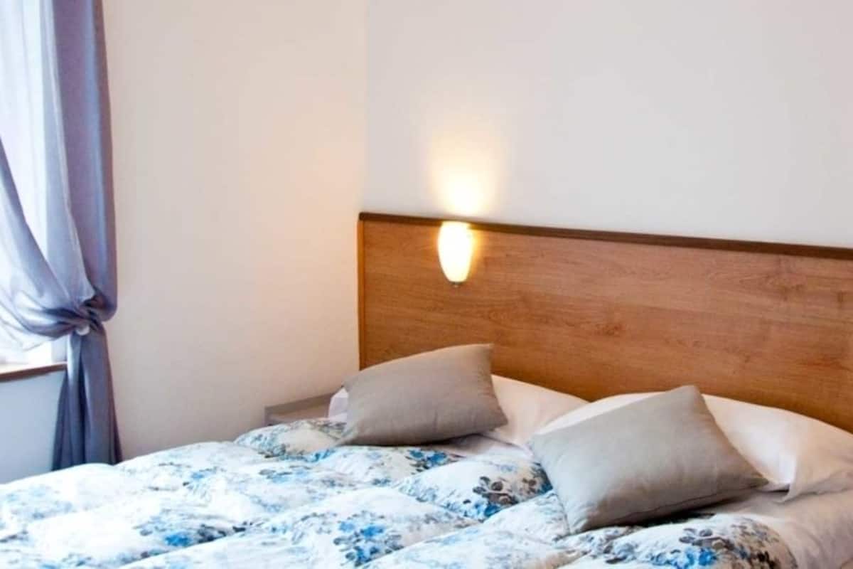 A bed with a floral bedspread, two pillows, and two wall-mounted lights.