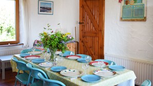 A dining area with a table set for four, chairs, a vase with flowers, and a wooden door. - The Song House (Falcarragh)