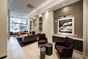 Eine moderne Hotelhalle mit Sitzgelegenheit, Kamin und einem großen gerahmten Kunstwerk an der Wand.