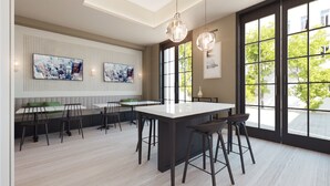 Une cuisine moderne dotée d’un îlot central, de tabourets de bar et de grandes fenêtres offrant une vue sur l’extérieur.