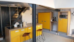 Una cocina compacta con armarios amarillos, un microondas y una cafetera.
