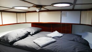 Una cama con ropa de cama y almohadas grises, un cabecero de madera e iluminación empotrada en el techo.