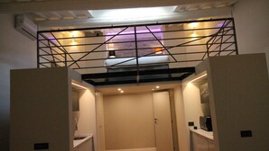 A compact room with a sloped ceiling, a visible staircase, and a small kitchenette area. - Tornabuoni Loft Apartment (Firenze)