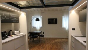 A modern kitchen with a dining area, wooden flooring, and a black lamp. - Tornabuoni Loft Apartment (Firenze)