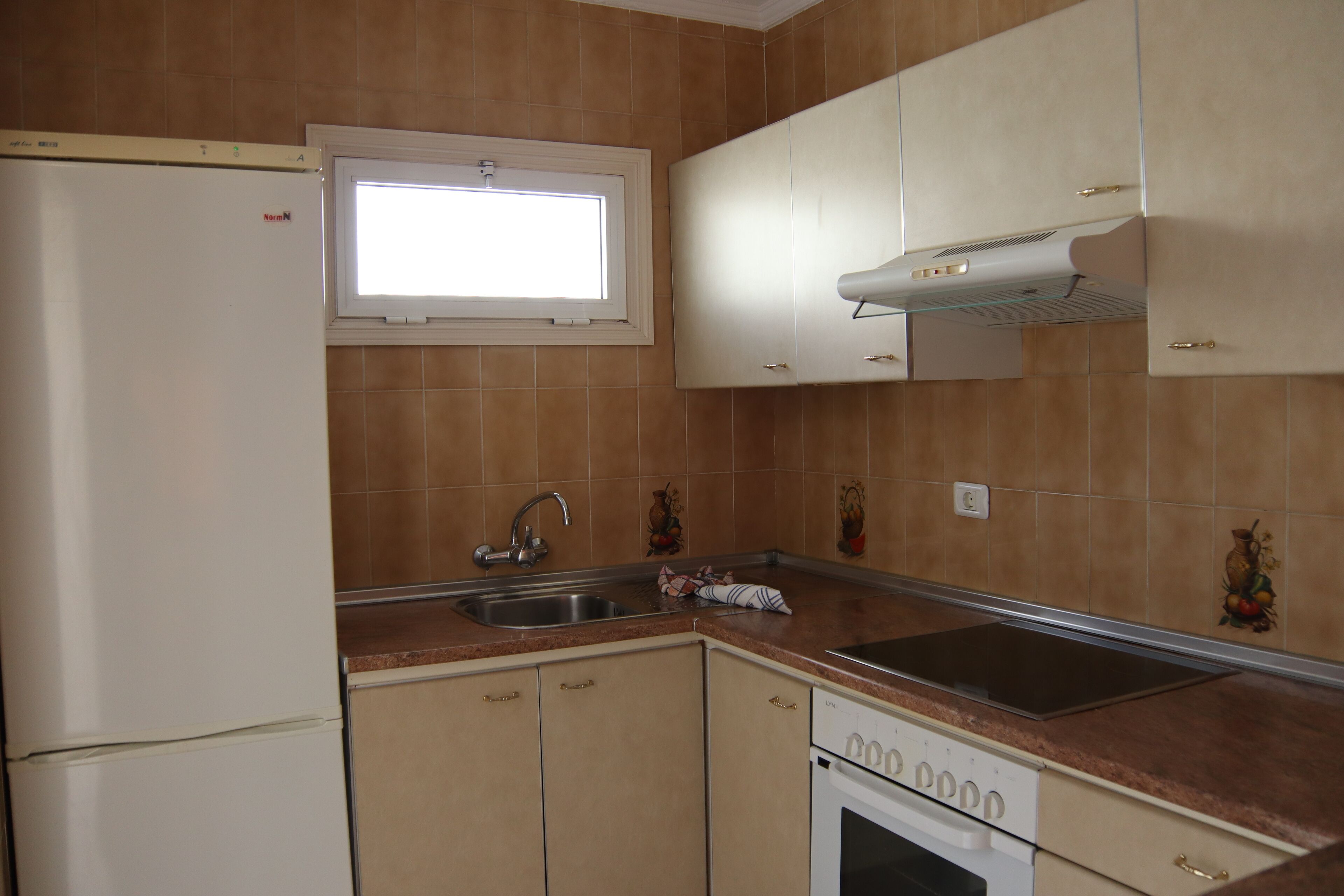 Una cucina con finestra, lavello, piano cottura e pensili.