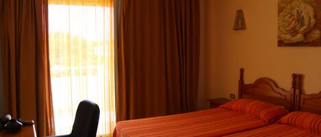 A hotel room with two beds, a chair, a desk, and a painting on the wall.