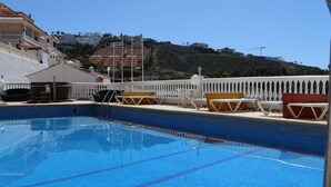 Une piscine avec des chaises longues et une clôture blanche.