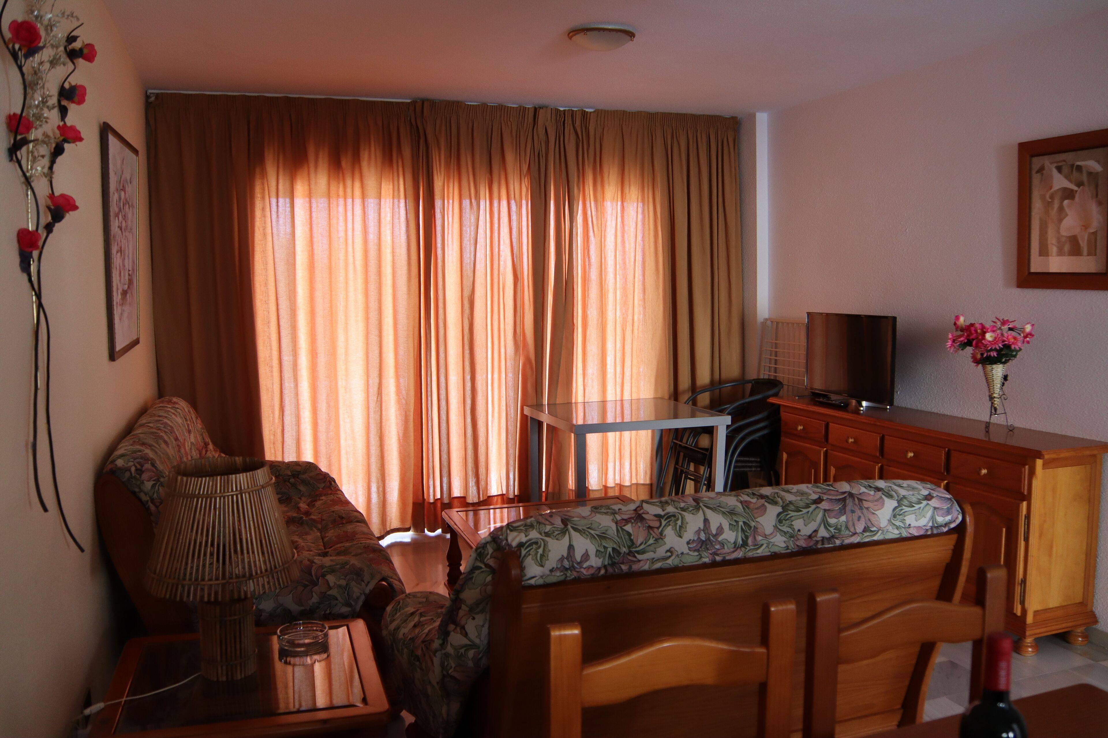 Una sala de estar con sofá, mesa de comedor, televisor y aparador.